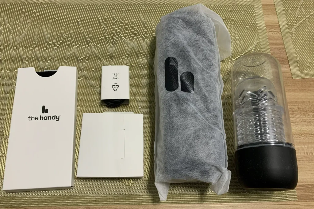 The Handy 2 Pro wird aus der Verpackung genommen, daneben liegen Zubehörboxen und der TrueGrip Cup.