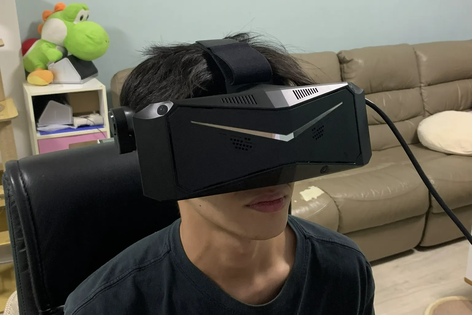 Front view of a person wearing the Pimax Crystal Light headset, showing the headset size, angular front design, and connected cable.