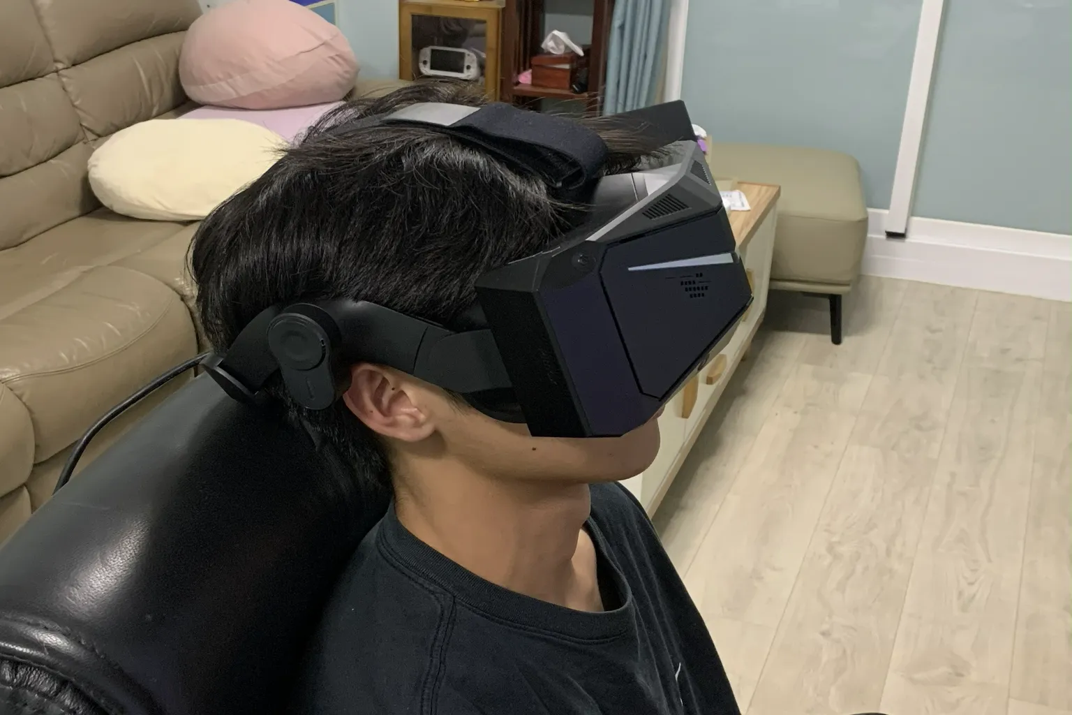 Side view of a person wearing the Pimax Crystal Light headset while seated, showing the large front body, head strap, and rear cable.