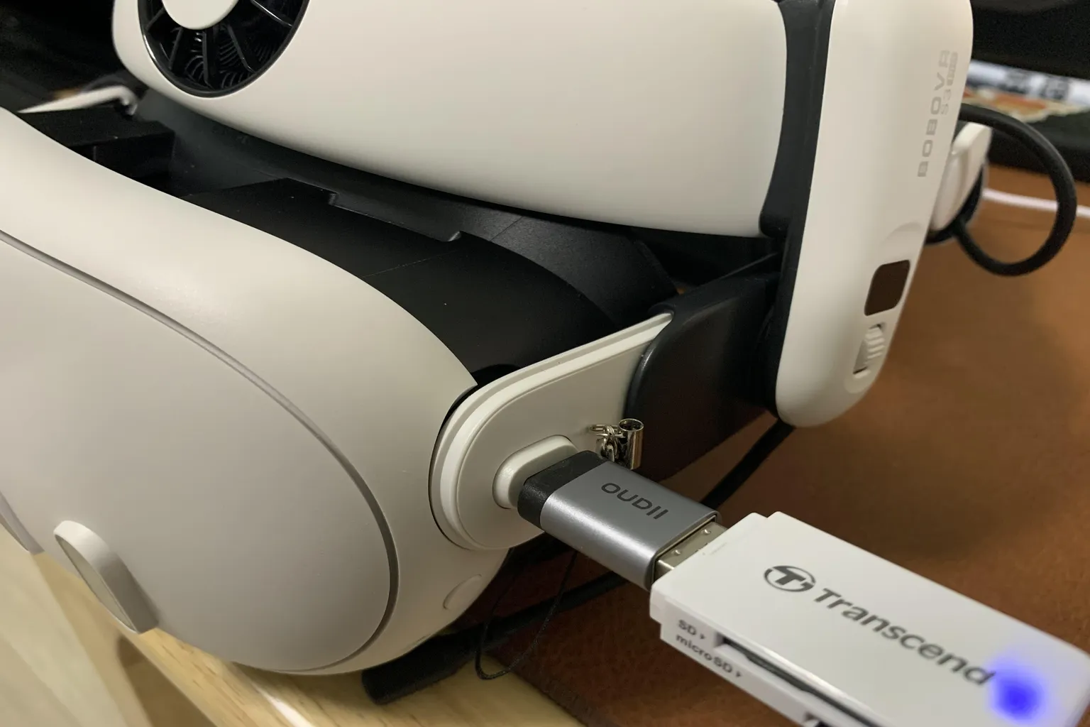 Unidad USB conectada físicamente a un visor Meta Quest mediante un adaptador y un lector de tarjetas.