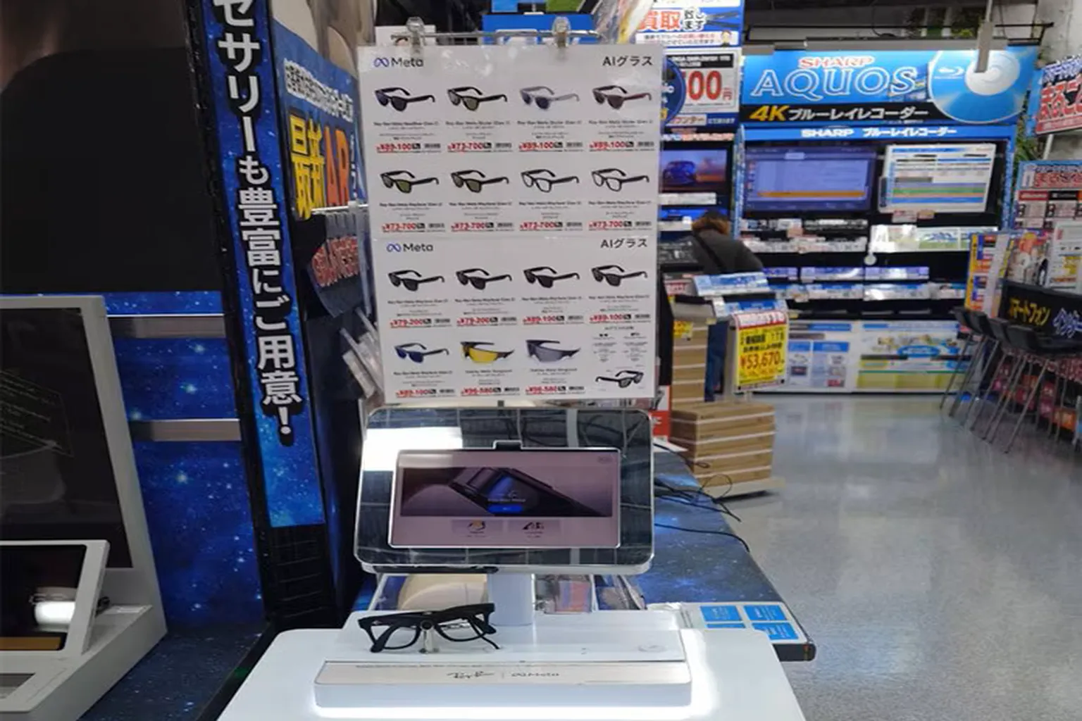 日本 Yodobashi Camera 電器賣場的 Meta AI 智慧眼鏡展示區，現場陳列 Ray-Ban Meta 試戴眼鏡、各款 AI 眼鏡型號與日圓售價資訊。